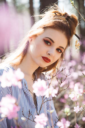 Japanese-style girl in a flowering forest among pink flowers in springの写真素材