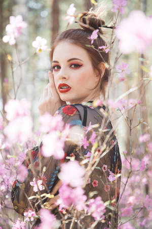 Japanese-style girl in a flowering forest among pink flowers in springの写真素材