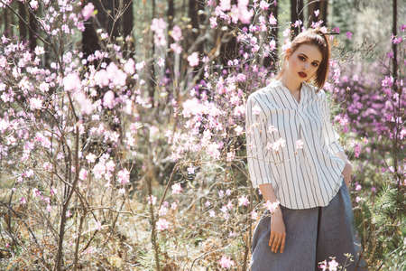 Japanese-style girl in a flowering forest among pink flowers in springの写真素材
