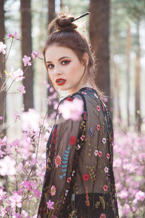 Japanese-style girl in a flowering forest among pink flowers in springの写真素材