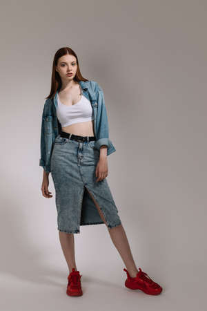Girl in jeans and red sneakers posing on a white background .の写真素材