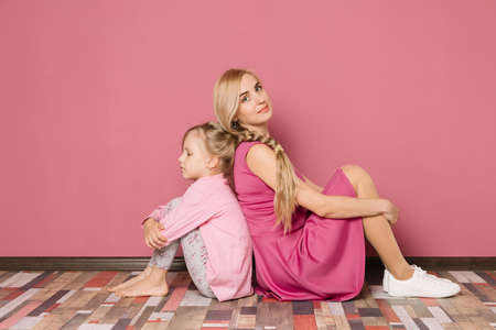 mother with daughter in pink clothes on a pink backgroundの写真素材