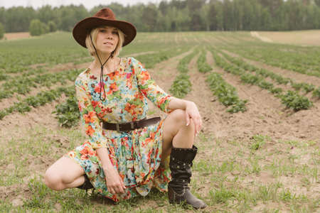 Girl in a cowboy hat and boots in the fieldの写真素材