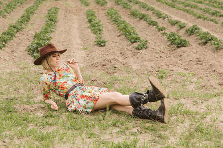 Girl in a cowboy hat and boots in the fieldの写真素材