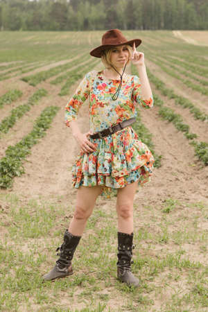 Girl in a cowboy hat and boots in the fieldの写真素材