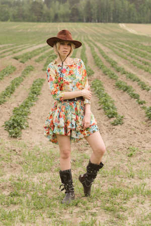 Girl in a cowboy hat and boots in the fieldの写真素材