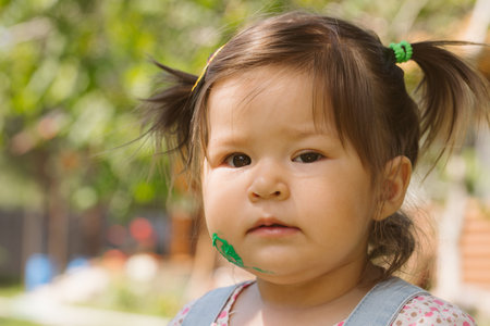 Two little girls sisters paint with finger paints on the street on the grass in summerの写真素材
