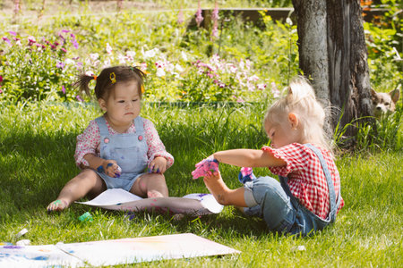 Two little girls sisters paint with finger paints