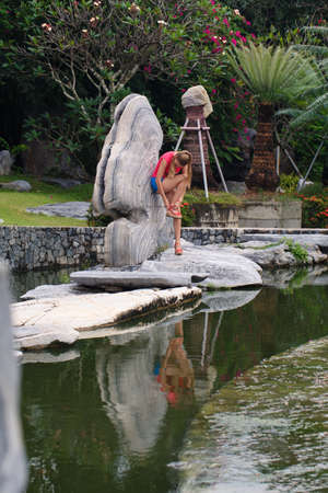 Beautiful girl in a pink t-shirt and blue shorts in a tropical gardenの写真素材
