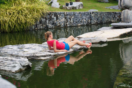Beautiful girl in a pink t-shirt and blue shorts in a tropical gardenの写真素材