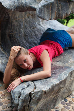Beautiful girl in a pink t-shirt and blue shorts in a tropical gardenの写真素材