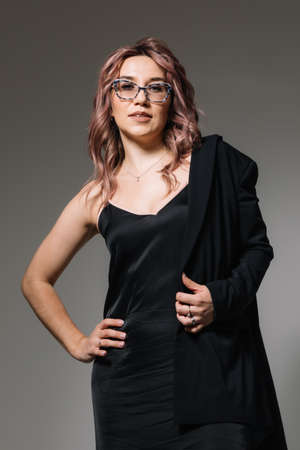 Fashion portrait of a business woman in glasses in a black dress and jacketの写真素材