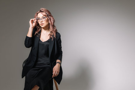 Business woman in glasses, a black dress and a jacket offers cosmetics