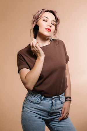 Girl makeup artist in glasses on a beige background shows cosmeticsの写真素材