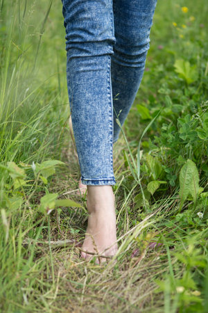 Beautiful young female legs walking on the grass in summerの写真素材