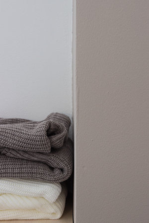 A stack of wool sweaters on the shelf. Grey and white sweater. Warm and cozy. Knitted clothing....