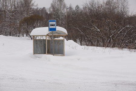 A bus stop full of snow on one of the snow-covered streets in the center of the village on a winter evening. Russia, Siberia.の写真素材
