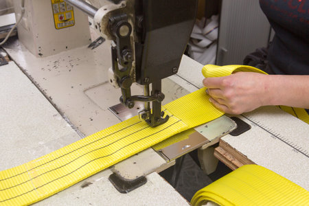 Industrial sewing machine sews a webbing sling. Manufacture of textile slings and tie straps