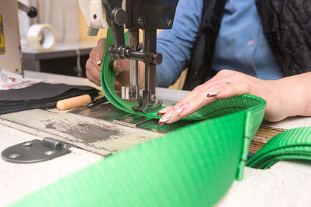Industrial sewing machine sews a webbing sling. Manufacture of textile slings and tie straps