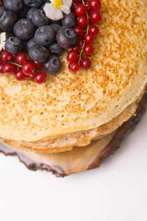 a large stack of pancakes with red sweet berries.