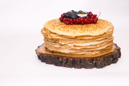 a large stack of pancakes with red sweet berries.