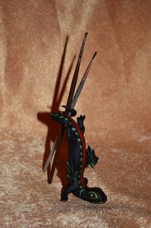Tiny black, green and red dragon holding brushesの写真素材
