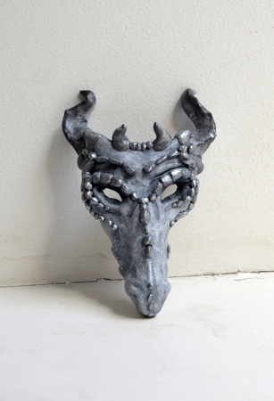 Dragon mask standing by a white wallの写真素材