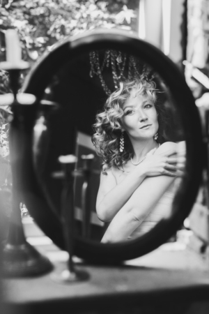 Reflection of beautiful woman admiring herself in the mirror, black and white shotの写真素材
