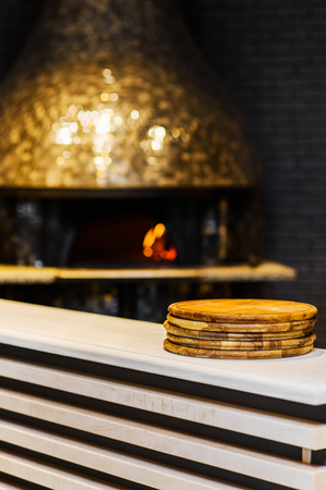 Stack of wooden boards in front of traditional pizza ovenの写真素材