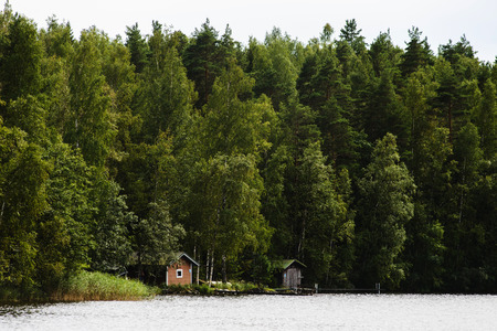 Far away summer view on finnish sauna buildings at forest near lakeの写真素材