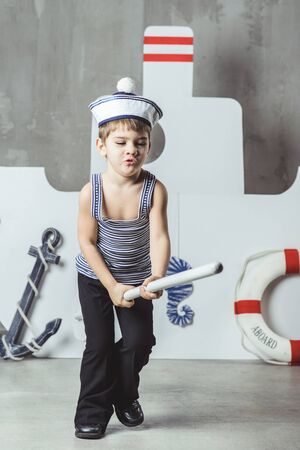 Cabin boy playing with paddle in front of stylized shipの写真素材