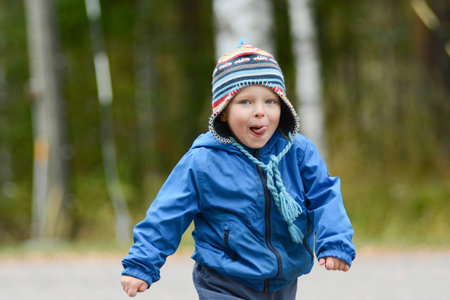 Happy cheerful boy with blue eyes running tongue outの写真素材