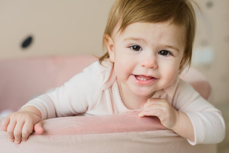 cute baby girl playing with balls in ball pool at home, pastel pink colors, close upの写真素材