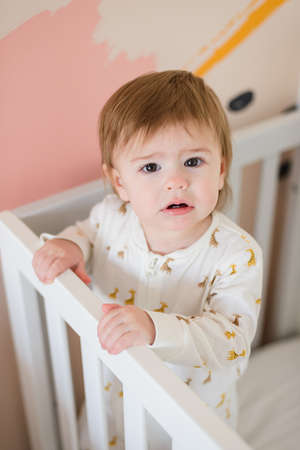Sleepy cute baby girl standing in bed in the morningの写真素材