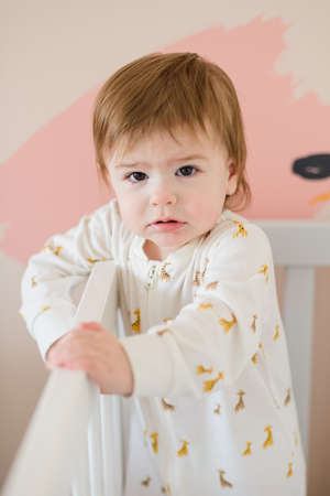Sleepy cute baby girl standing in bed in the morningの写真素材