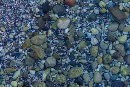 Sea stones under clear water, blue background, top view