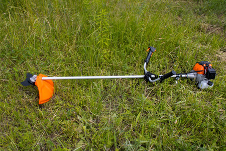 Trimmer brushcutter petrol engine on the green lawn