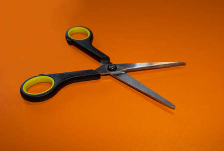 Office scissors open in black and yellow on an orange backgroundの写真素材