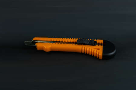 Office knife orange color close-up on a dark gray backgroundの写真素材
