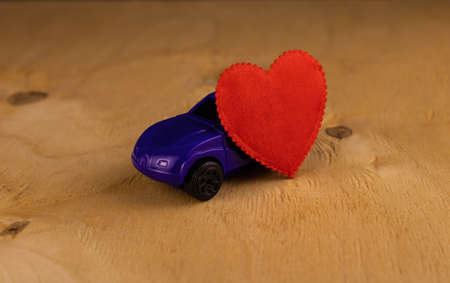Model of a blue car with a heart on a light wooden backgroundの写真素材