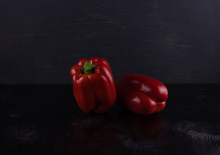 Two red Mature sweet peppers close up on a dark wooden background
