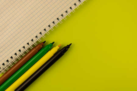 Multi-colored markers and a notebook on a spring on a light green background, copy space.の写真素材