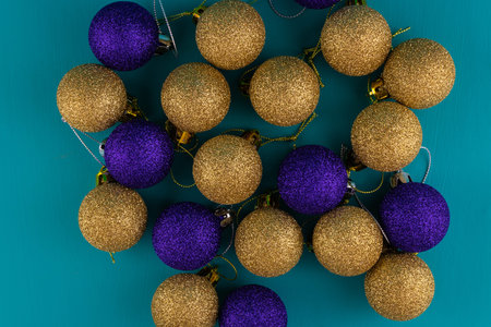 Multicolored shiny Christmas balls on a turquoise background, top view.