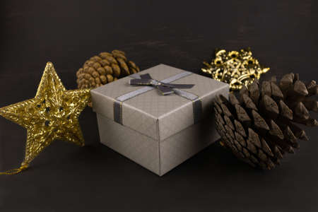 Gift box with pine cones and Christmas tree toys close-up on a dark background.の写真素材