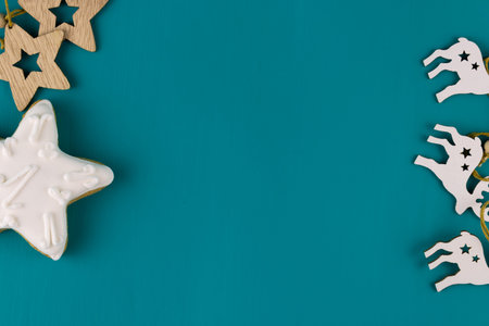 Gingerbread and wooden Christmas toys on a turquoise background. Top view, copy space.