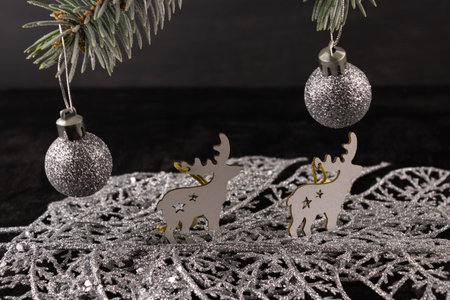 Christmas decor on spruce branches and wooden figures of a deer on a dark wooden background.の写真素材