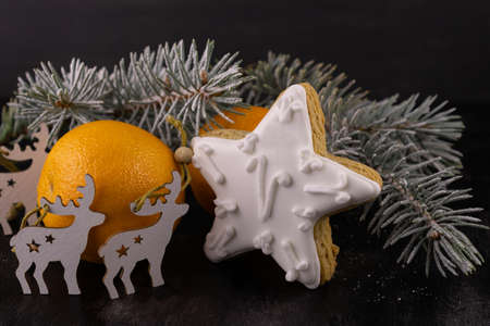 Spruce, tangerines, Christmas decorations and gingerbread close-up on a dark wooden background.の写真素材
