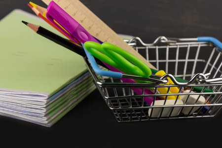 School supplies in a basket and a stack of notebooks on a dark background