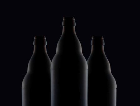 Three bottles of dark glass on a dark background.
