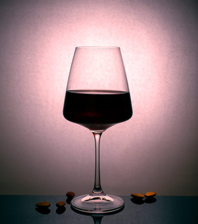 A glass of red wine and almonds in close-up.